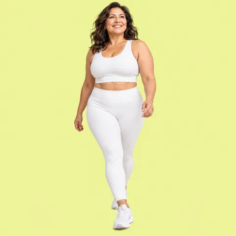 A smiling woman with dark hair walking in white activewear