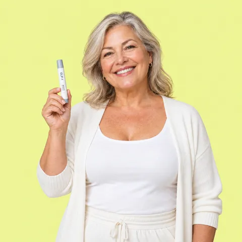A smiling woman in a cream cardigan holding up an injection pen
