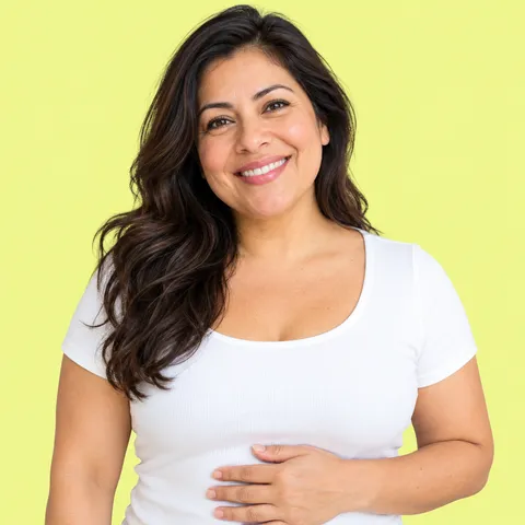 A smiling woman in a white T-shirt with one hand resting on her stomach